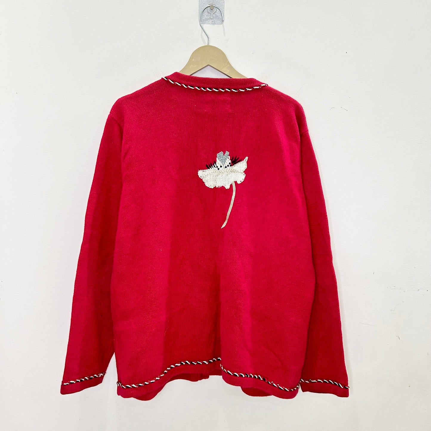 Red sweater with a white design on a hanger against a white background