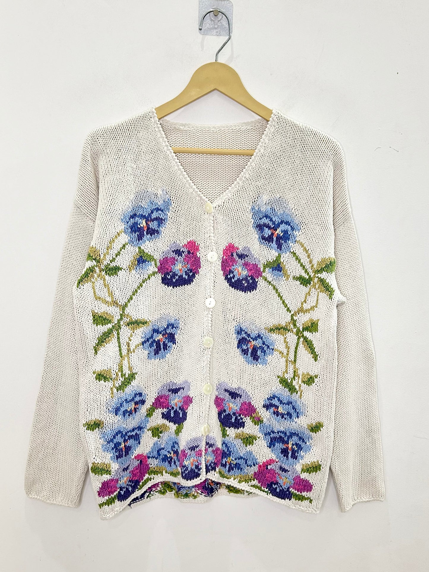 Floral patterned cardigan on a hanger against a white background