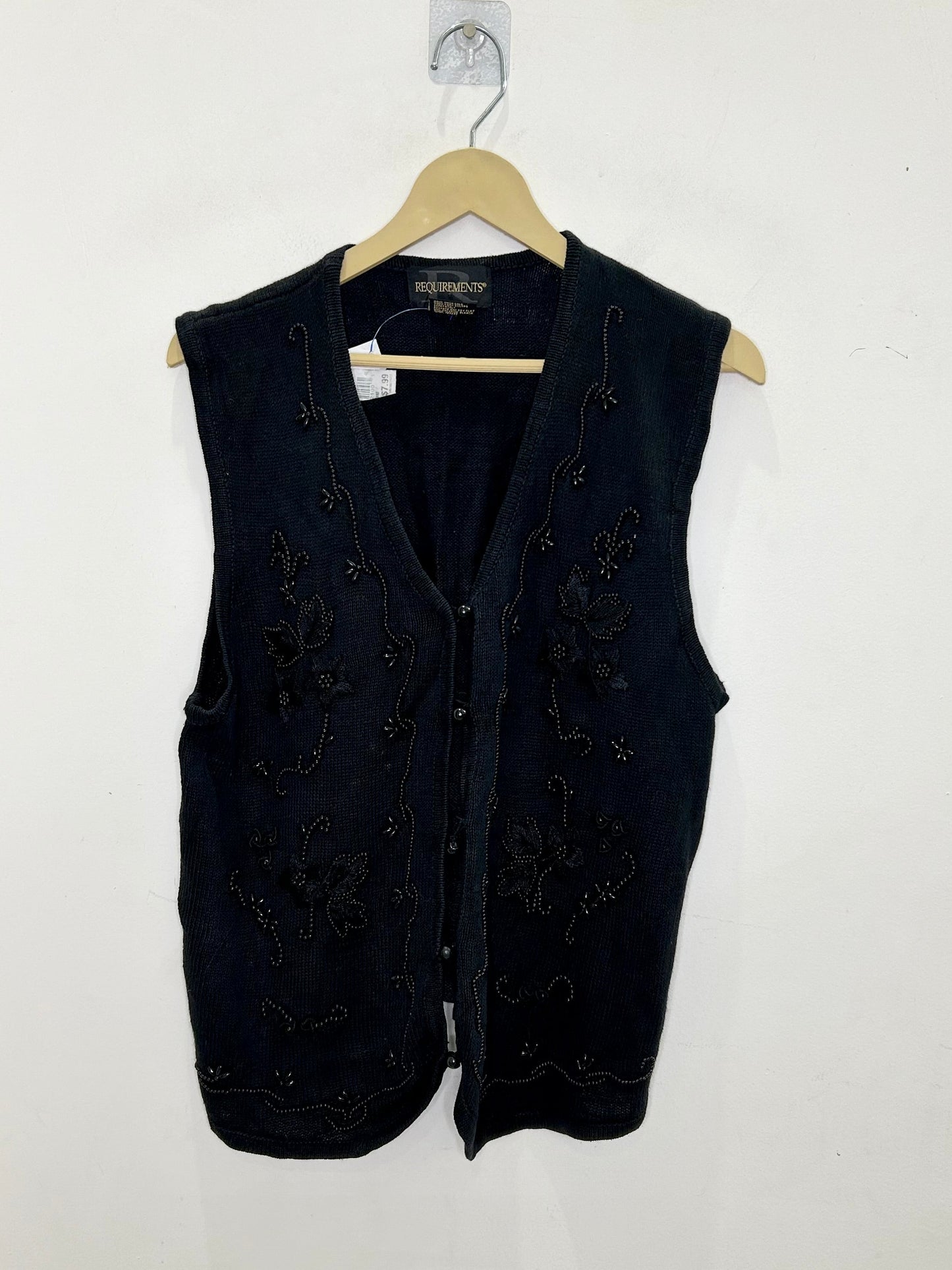 Black vest on a hanger against a white background