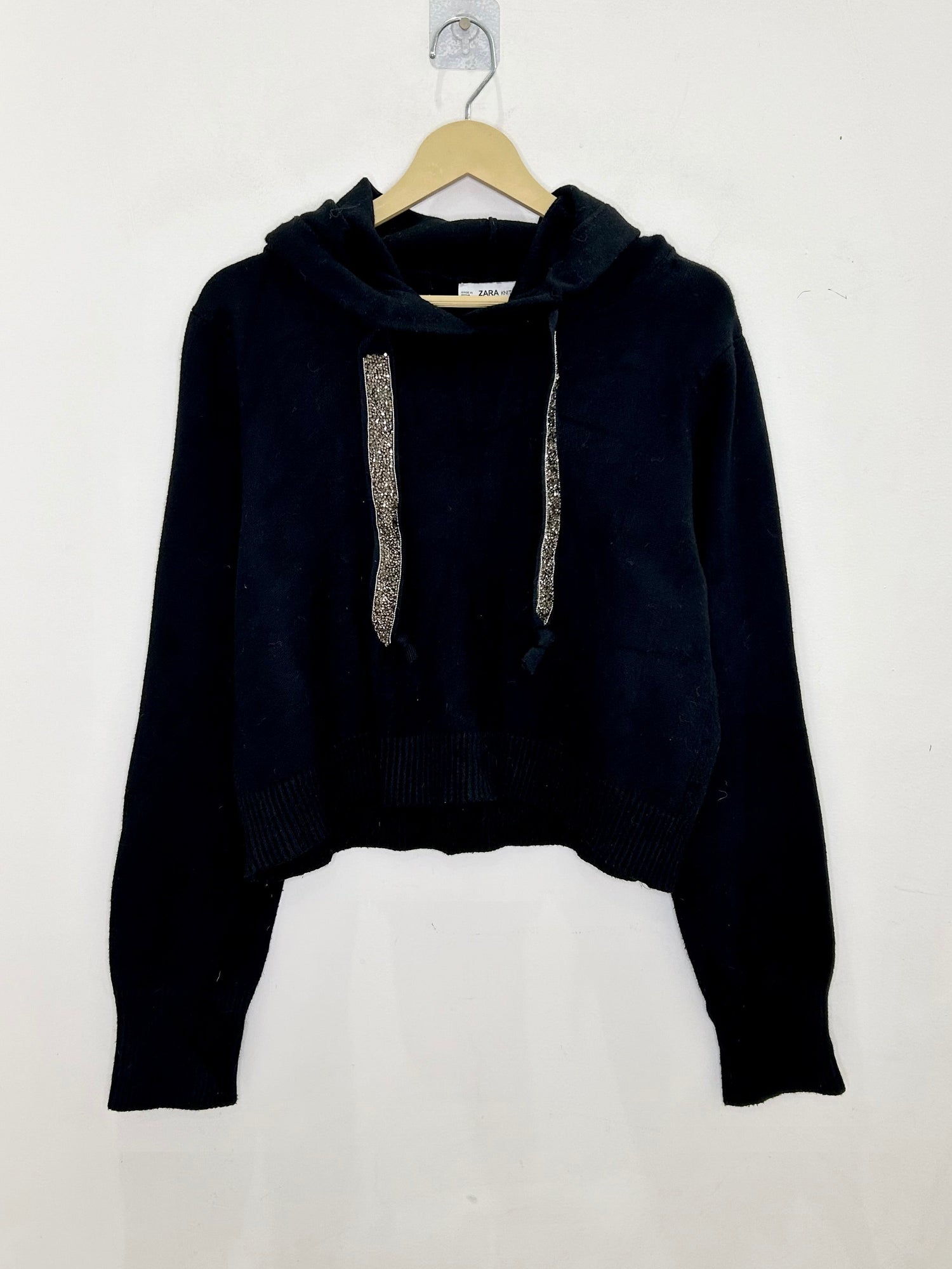 Black hoodie with glittery drawstrings on a white background